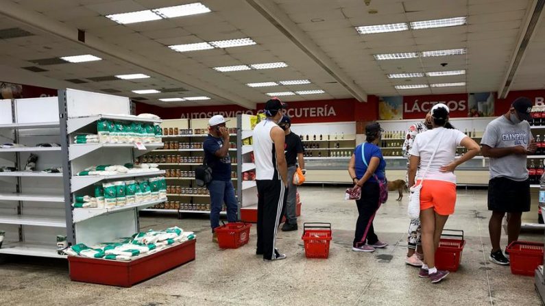 Personas hacen fila para pagar sus compras en un supermercado, en Caracas (Venezuela). EFE/Rayner Peña/Archivo