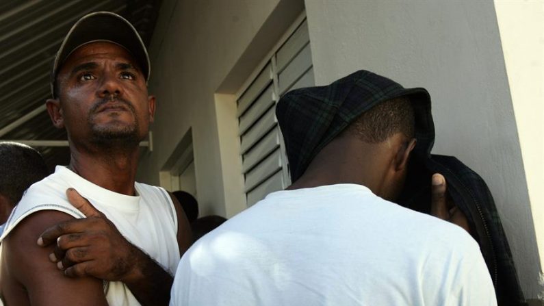 Una persona indocumentada se cubre la cabeza y el rostro mientras otra observa en San Juan, Puerto Rico. EFE/Orlando Barría/Archivo
