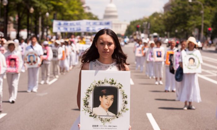 Una mujer sostiene una foto de un hombre asesinado por la persecución del régimen chino a Falun Gong, durante un desfile en Washington el 17 de julio de 2014. (Larry Dye/The Epoch Times)