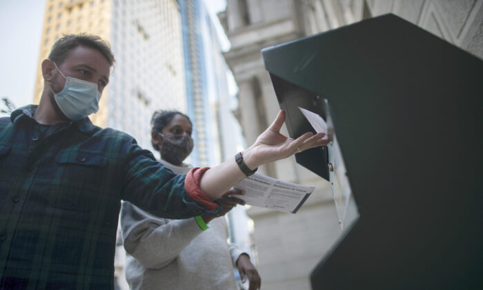Dos personas introducen su boleta de voto anticipado en un buzón situado junto al Ayuntamiento de Filadelfia (Pensilvania) el 17 de octubre de 2020. (Mark Makela/Getty Images)