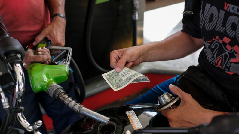 Un hombre paga con un billete de un dólar americano después de llenar el depósito de su moto en una gasolinera el 26 de junio de 2019 en Caracas, Venezuela. (Matias Delacroix/Getty Images)