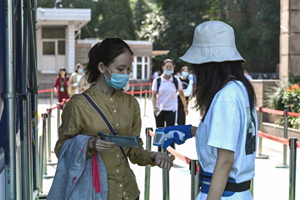 A una estudiante (izq.) se le revisa la temperatura corporal antes de ingresar a una escuela para rendir el Examen Nacional de Ingreso a la Universidad (NCEE), conocido como Gaokao, en Nanjing, en la provincia de Jiangsu, en el este de China, el 7 de julio de 2020. (STR/AFP a través de Getty Images)