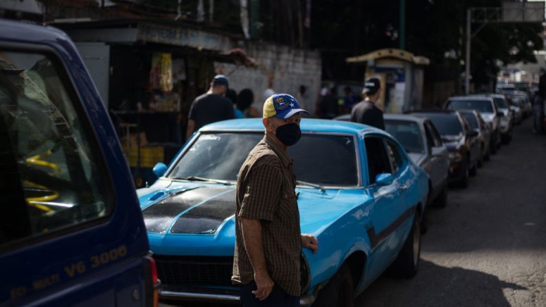 Un hombre espera junto a su coche en una fila para repostar el tanque de su vehículo cerca de una gasolinera en Caracas (Venezuela) el 5 de octubre de 2020. (Foto de CRISTIAN HERNANDEZ/AFP vía Getty Images)