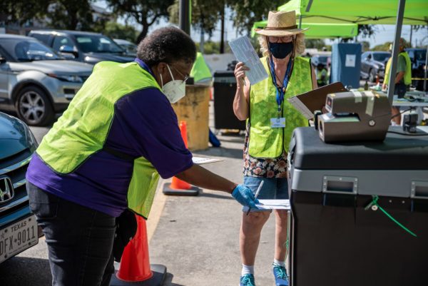 Los trabajadores depositan las boletas de los votantes en una caja segura en un lugar de entrega de boletas el 13 de octubre de 2020 en Austin, Texas (EE.UU.). (Foto de Sergio Flores/Getty Images)
