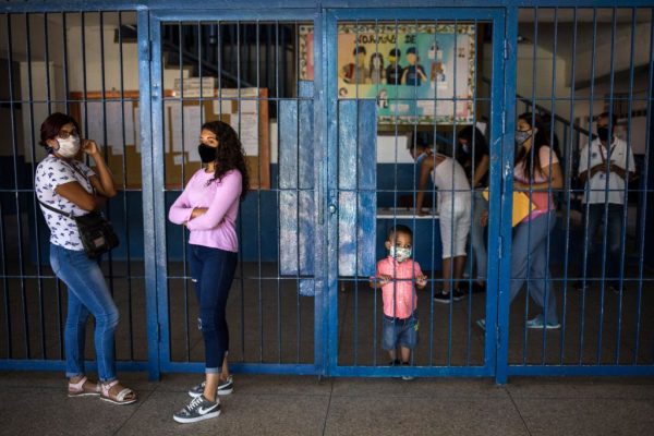 Padres de los estudiantes son vistos en la escuela secundaria pública "Tito Salas" durante el día de registro del año escolar 2020-2021 en el barrio de Las Minas de Baruta, Caracas (Venezuela), el 7 de octubre de 2020, en medio de la nueva pandemia de covid-19. (Foto de CRISTIAN HERNANDEZ/AFP vía Getty Images)