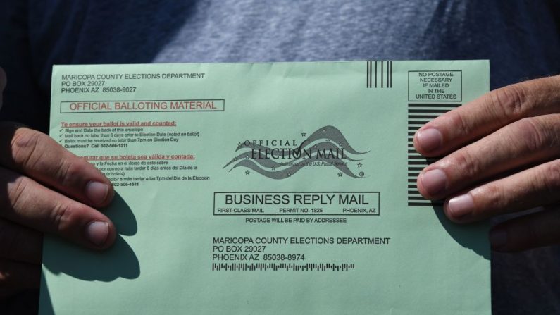 Una votante de las elecciones generales de Estados Unidos muestra el sobre de su boleta por correo en un lugar de votación anticipada en Phoenix, Arizona, el 16 de octubre de 2020. (Robyn Beck / AFP/ a través de Getty Images)