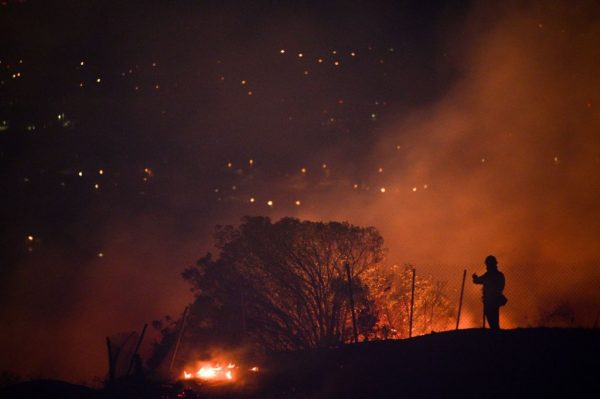 Los bomberos se posicionan en un área residencial y monitorean las llamas que suben por una cresta hacia las casas en el incendio de Blue Ridge en Yorba Linda, California, el 26 de octubre de 2020. (Foto de ROBYN BECK/AFP vía Getty Images)