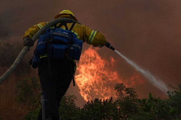 Un bombero extingue las llamas en una zona residencial en el incendio de Blue Ridge en Yorba Linda, California, el 26 de octubre de 2020. (Foto de ROBYN BECK/AFP vía Getty Images)