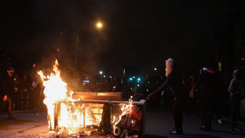 Manifestantes se paran cerca de una barricada en llamas en Filadelfia el 27 de octubre de 2020, durante una protesta. Cientos de personas se manifestaron en Filadelfia la noche del 27 de octubre, con saqueos y violencia. Los nuevos disturbios se produjeron un día después de la muerte de Walter Wallace, de 27 años, mientras portaba un cuchillo  (GABRIELLA AUDI/AFP vía Getty Images)