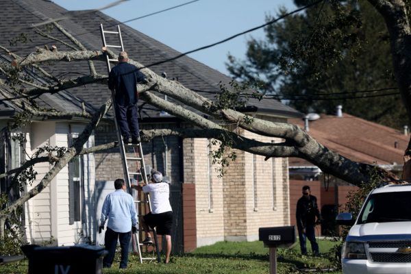 Los residentes quitan un árbol que cayó en un tejado después del huracán Zeta el 29 de octubre de 2020 en Chalmette, Louisiana (EE.UU.). (Foto de Sandy Huffaker/Getty Images)