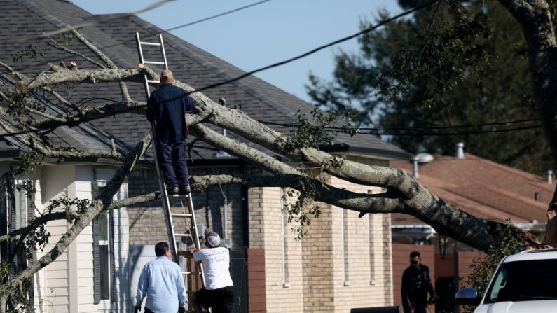 Los residentes quitan un árbol que cayó en un tejado después del huracán Zeta el 29 de octubre de 2020 en Chalmette, Louisiana (EE.UU.). (Foto de Sandy Huffaker/Getty Images)