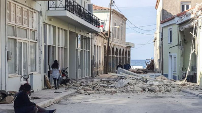 La gente pasa por delante de una casa destruida después de un terremoto en la isla de Samos (Grecia) el 30 de octubre de 2020. (Foto de STR/Eurokinissi/AFP vía Getty Images)