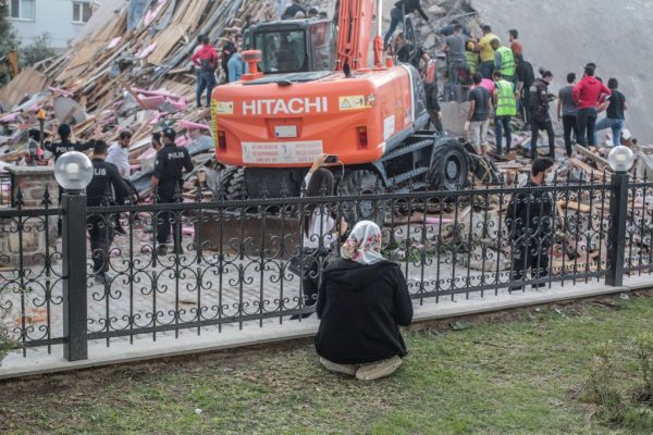 Una mujer se sienta en el suelo mientras los voluntarios limpian los escombros y buscan supervivientes en un edificio derrumbado después de que un fuerte terremoto golpeara la costa occidental del país y partes de Grecia, matando a al menos 4 personas e hiriendo a 152, en Izmir (Turquía), el 30 de octubre de 2020. (Foto de MERT CAKIR/AFP vía Getty Images)