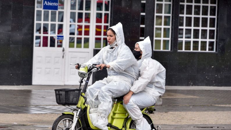 Mujeres con trajes protectores conducen una motocicleta eléctrica en el área de Kennedy el 01 de junio de 2020 en Bogotá, Colombia. (Guillermo Legaria/Getty Images)