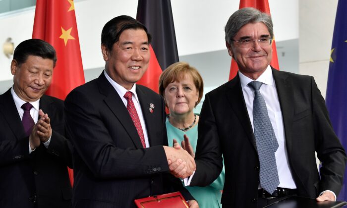 La canciller alemana Angela Merkel (c) y el mandatario chino Xi Jinping (i) observan cómo el presidente de Siemens, Joe Kaeser (dcha.), da la mano a un socio chino durante una ceremonia de firma de contratos comerciales sino-germanos en la cancillería de Berlín, el 5 de julio de 2017. (John Macdougall/AFP vía Getty Images)
