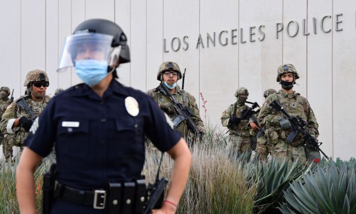 Un oficial de policía se encuentra con miembros armados de la Guardia Nacional enfrentando a los manifestantes frente al Departamento de Policía de Los Ángeles en Los Ángeles, California, el 1 de junio de 2020. (Frederic J. Brown/AFP vía Getty Images)