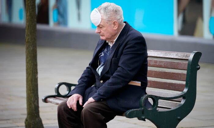 Un hombre con una mascarilla de espalda descansando en un banco durante la pandemia del virus del PCCh en Oldham, Inglaterra, el 29 de julio de 2020. (Christopher Furlong/Getty Images)
