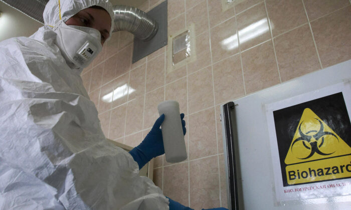 Un trabajador de un laboratorio ruso manipula un frasco que contiene la cepa del virus de la gripe porcina H1N1 en San Petersburgo el 13 de mayo de 2009. (Kirill Sirotyuk/AFP vía Getty Images)