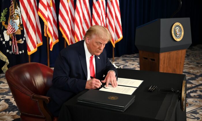 El presidente Donald Trump firma órdenes ejecutivas que extienden el alivio económico del virus del PCCh, durante una conferencia de prensa en Bedminster, Nueva Jersey, el 8 de agosto de 2020. (Jim Watson/AFP vía Getty Images)