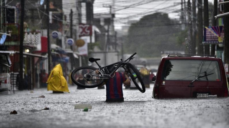 Un hombre carga una bicicleta mientras camina por una calle inundada el 30 de octubre de 2020, debido a las intensas lluvias en la ciudad de Villahermosa, en el estado de Tabasco (México). EFE/Jaime Avalos