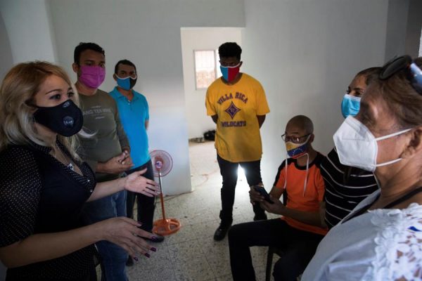 La abogada Guadalupe Vargas (i) conversa con un grupo de migrantes venezolanos en una pequeña casa, apenas equipada y por el momento sin electricidad, que les han conseguido en una zona humilde, el 20 de octubre de 2020, en Santo Domingo (República Dominicana). EFE/ Orlando Barría