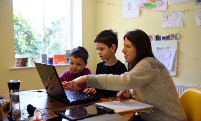 Niños con su madre estudiando en una plataforma de aprendizaje online durante el bloqueo del virus del PCCh, en Huddersfield, Inglaterra, el 23 de marzo de 2020. (Oli Scarff/AFP a través de Getty Images)