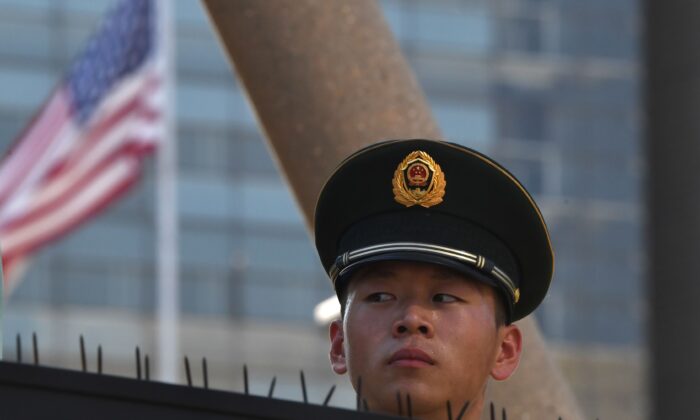 Un policía paramilitar mira más allá de la bandera de Estados Unidos en los recintos de la embajada, en Beijing, el 26 de julio de 2018, luego de una explosión cerca de las instalaciones de la embajada de Estados Unidos. (Greg Baker/AFP a través de Getty Images)
