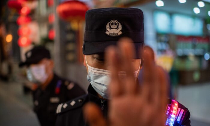 Un oficial de policía con mascarilla facial intenta evitar que un reportero tome fotografías en una calle afuera de un centro comercial en Beijing el 13 de octubre de 2020. (Nicolas Asfouri/AFP a través de Getty Images)