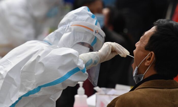 Un trabajador de la salud toma una muestra de un residente para ser analizada para el virus del PCCh como parte de un programa de pruebas masivas después de un nuevo brote del coronavirus en Qingdao, una ciudad ubicada en la provincia de Shandong en el este de China el 13 de octubre de 2020. (STR/AFP vía Getty Images)