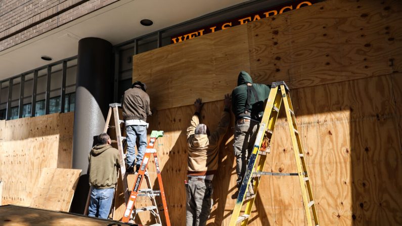 Trabajadores tapan los escaparates de las tiendas como parte de los preparativos para el día de las elecciones, en el centro de Washington, cerca de la Casa Blanca, el 2 de noviembre de 2020. (Charlotte Cuthbertson/The Epoch Times)