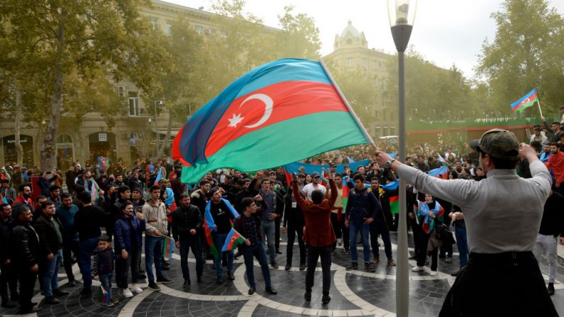 Los azerbaiyanos sostienen su bandera nacional mientras celebran en las calles de la capital Bakú el 10 de noviembre de 2020, después de que Armenia y Azerbaiyán acordaran un alto el fuego tras una serie de victorias azeríes en la lucha por la disputada región de Nagorno-Karabaj. (Foto de TOFIK BABAYEV / AFP a través de Getty Images)