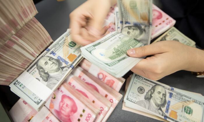 Un empleado de un banco chino cuenta billetes de 100 yuanes y dólares estadounidenses en una ventanilla de un banco en Nantong, en la provincia de Jiangsu, al este de China, el 6 de agosto de 2019. (STR/AFP vía Getty Images)