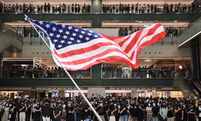 La gente agita la bandera de Estados Unidos durante una manifestación flash mob dentro de un centro comercial, en el distrito de Sha Tin, en Hong Kong, el 13 de octubre de 2019. (Philip Fong/AFP a través de Getty Images).