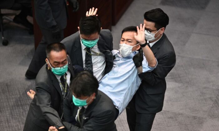 El legislador prodemocrático Raymond Chan (C) se deja llevar por la seguridad tras el forcejeo desencadenado en el Consejo Legislativo (LegCo) de Hong Kong el 8 de mayo de 2020. (Anthony Wallace/AFP vía Getty Images)