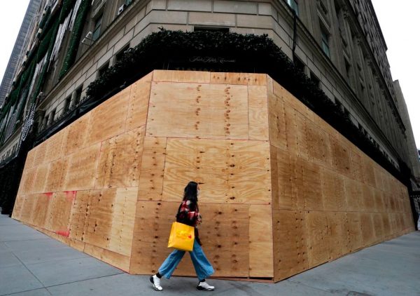 Una mujer camina por una tienda de Saks Fifth Avenue en Nueva York el 1 de noviembre de 2020, vista tapiada mientras hacen planes para posibles disturbios civiles durante la carrera presidencial de Estados Unidos por la Casa Blanca. (Foto de TIMOTHY A. CLARY / AFP a través de Getty Images)