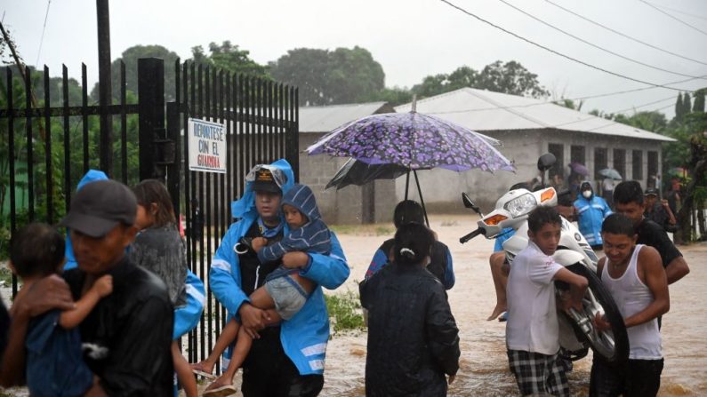 Oficiales de la Policía Nacional y pobladores rescatan a niños en el barrio de Alemania, que fue inundado por el desborde del arroyo La Arenera, debido a las fuertes lluvias provocadas por el huracán Eta, ahora degradado a tormenta tropical, en la ciudad de El Progreso. departamento de Yoro, 260 kms al norte de Tegucigalpa (Honduras), el 4 de noviembre de 2020. (Foto de ORLANDO SIERRA / AFP vía Getty Images)