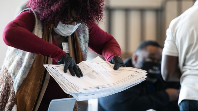 Un trabajador del condado de Fulton mueve una pila de boletas de votos en ausencia en el State Farm Arena el 6 de noviembre de 2020 en Atlanta, Georgia. ( Jessica McGowan/Getty Images)