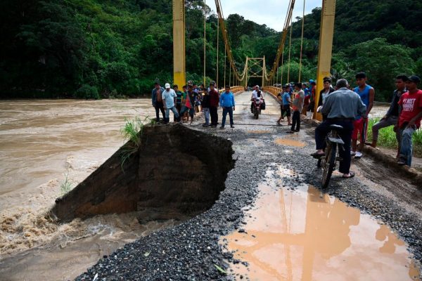 La gente observa los daños causados ​​por las fuertes lluvias provocadas por el huracán Eta, ahora degradado a tormenta tropical, en un puente sobre el río Cahaboncito inundado en Panzos, Alta Verapaz, 220 km al norte de la ciudad de Guatemala el 6 de noviembre de 2020. (Foto de JOHAN ORDONEZ / AFP a través de Getty Images)