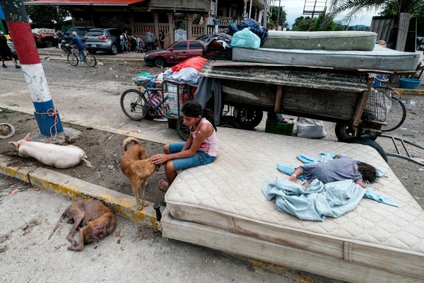 Una niña afectada por las inundaciones acaricia a un perro cuando otra niña pequeña duerme junto a ella en un colchón en la carretera principal del municipio el 6 de noviembre de 2020 en Cortes, Honduras. (Foto de Yoseph Amaya / Getty Images)