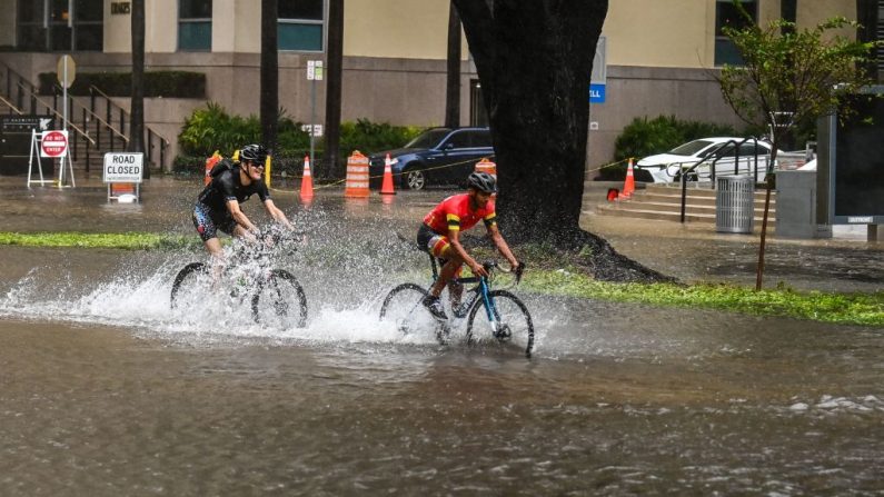 Los ciclistas recorren la calle inundada durante las fuertes lluvias y el viento mientras la tormenta tropical Eta se acerca al sur de Florida, en Miami, Florida (EE.UU.), el 9 de noviembre de 2020. (Foto de CHANDAN KHANNA / AFP a través de Getty Images)