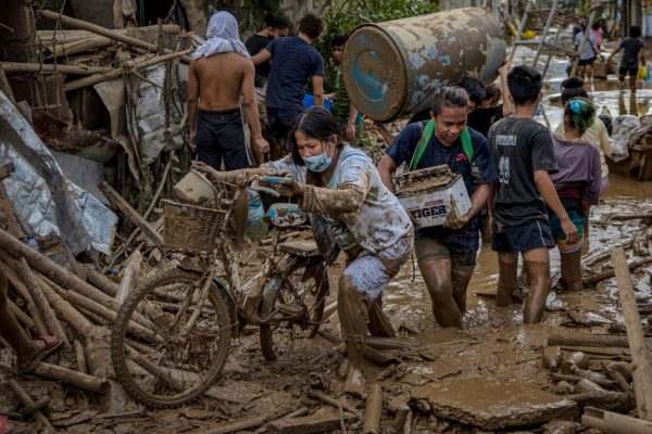 Los residentes cargan sus pertenencias mientras atraviesan el agua fangosa que sumergió una aldea después del tifón Vamco el 14 de noviembre de 2020 en Rodríguez, provincia de Rizal, Filipinas. (Foto de Ezra Acayan / Getty Images)