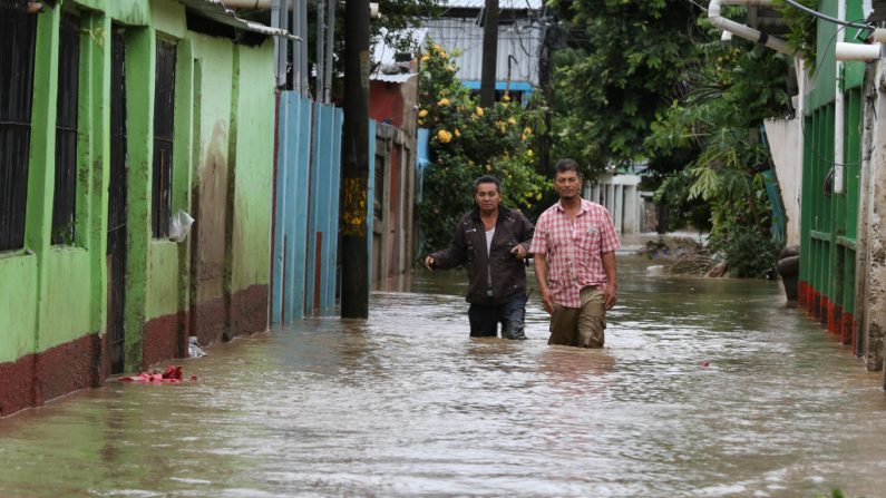 La gente vadea por una calle inundada por el desborde del río Chamelecón en el municipio de La Lima, departamento de Cortés, norte de Honduras, el 18 de noviembre de 2020, tras el paso del huracán Iota. (Foto de WENDELL ESCOTO / AFP a través de Getty Images)