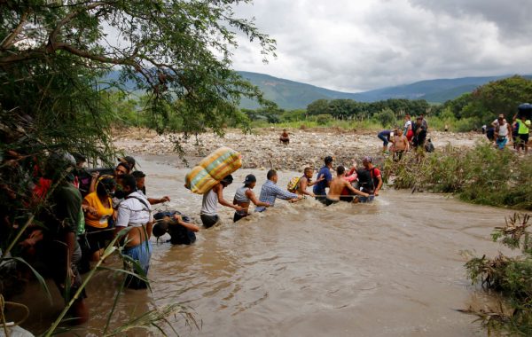 Los migrantes utilizan una cuerda para cruzar el río Táchira, la frontera natural entre Colombia y Venezuela, ya que la frontera oficial permanece cerrada debido a la pandemia de COVID-19 en Cúcuta, Colombia, el 19 de noviembre de 2020. (Foto de SCHNEYDER MENDOZA / AFP a través de Getty Images)