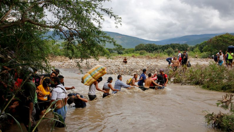Los migrantes utilizan una cuerda para cruzar el río Táchira, la frontera natural entre Colombia y Venezuela, ya que la frontera oficial permanece cerrada debido a la pandemia de COVID-19 en Cúcuta, Colombia, el 19 de noviembre de 2020. (Foto de SCHNEYDER MENDOZA / AFP a través de Getty Images)