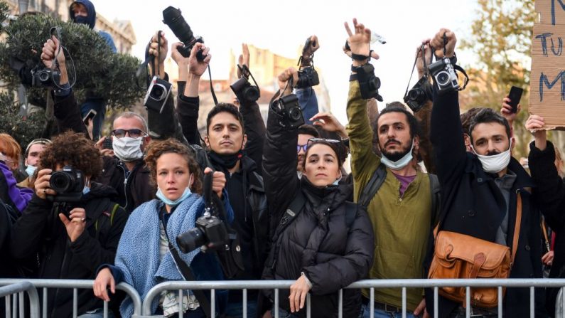 Los fotógrafos sostienen su cámara en el aire durante una manifestación en el Vieux-Port convocada por el movimiento de los "chalecos amarillos" (Gilets Jaunes) para protestar contra el proyecto de ley de "seguridad global" que busca limitar las filmaciones de los agentes de policía de guardia, en Marsella (Francia), el 21 de noviembre de 2020. (Foto de CLEMENT MAHOUDEAU / AFP a través de Getty Images)