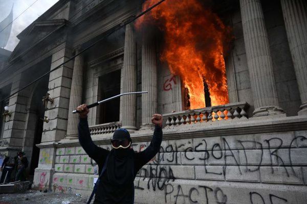 Manifestantes hacen un gesto después de incendiar una oficina del edificio del Congreso durante una protesta que exigía la dimisión del presidente Alejandro Giammattei, en la ciudad de Guatemala (Guatemala) el 21 de noviembre de 2020. (Foto de JOHAN ORDONEZ/AFP vía Getty Images)