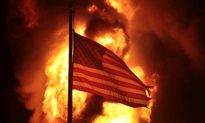 Una bandera estadounidense ondea frente a un edificio del departamento de correccionales después de que se incendiara durante una segunda noche de disturbios en Kenosha, Wisconsin, el 24 de agosto de 2020. (Scott Olson/Getty Images)