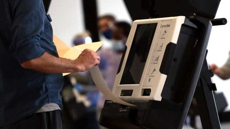 Un votante saca una boleta impresa de una máquina de votación en un centro de votación anticipada en el Mercado de la Unión el 27 de octubre de 2020 en Washington, DC. (Alex Wong/Getty Images)
