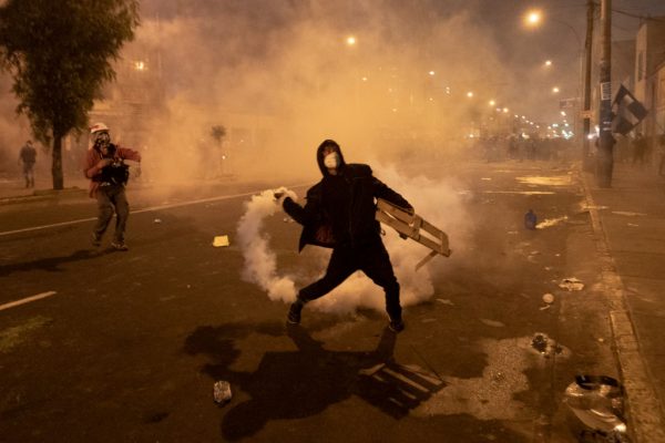 Un manifestante arroja una bomba de gas lacrimógeno a la policía antidisturbios durante una protesta contra el recién nombrado presidente interino Manuel Merino de Lama el 12 de noviembre de 2020 en Lima, Perú. (Foto de Renzo Salazar / Getty Images)