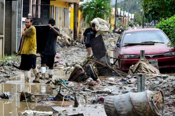 Dos hombres llevan un televisor sobre una calle cubierta de barro con escombros dejados por el huracán Iota de la Colonia Celeo Gonzales el 21 de noviembre de 2020 en San Pedro Sula, Honduras. (Foto de Yoseph Amaya / Getty Images)